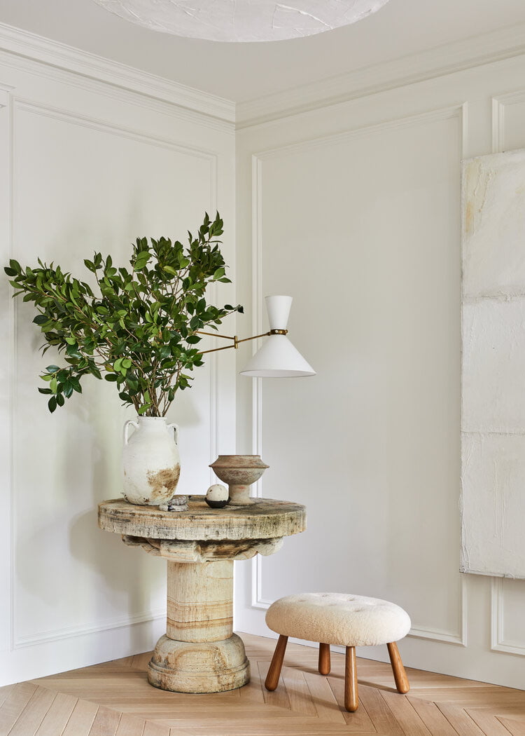 A classic and modern foyer set up with a table, stool and decor